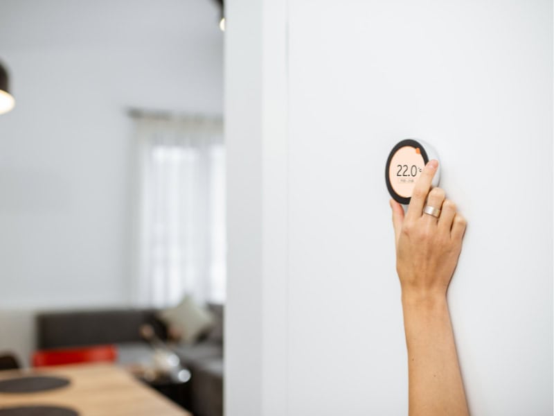 Person changing the heat setting on a smart thermostat.